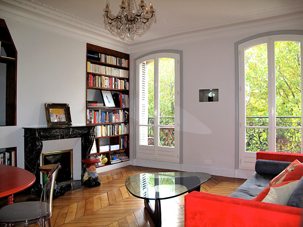 This is an example of a small bohemian open plan games room in Paris with grey walls, medium hardwood flooring, a standard fireplace, a reading nook, a stone fireplace surround and a built-in media unit.