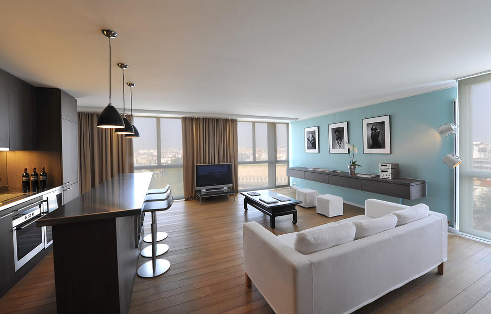 Стильный дизайн: большая открытая гостиная комната в стиле модернизм с домашним баром, синими стенами, светлым паркетным полом, отдельно стоящим телевизором и бежевым полом - последний тренд