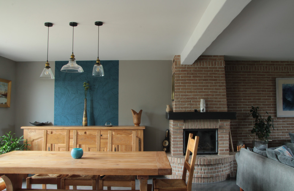 Cette image montre une salle de séjour design de taille moyenne et ouverte avec un sol gris, un mur gris, sol en béton ciré, un poêle à bois et un manteau de cheminée en brique.