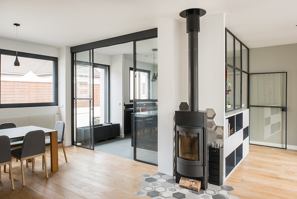 Example of a large trendy open concept light wood floor family room design in Paris with a wood stove