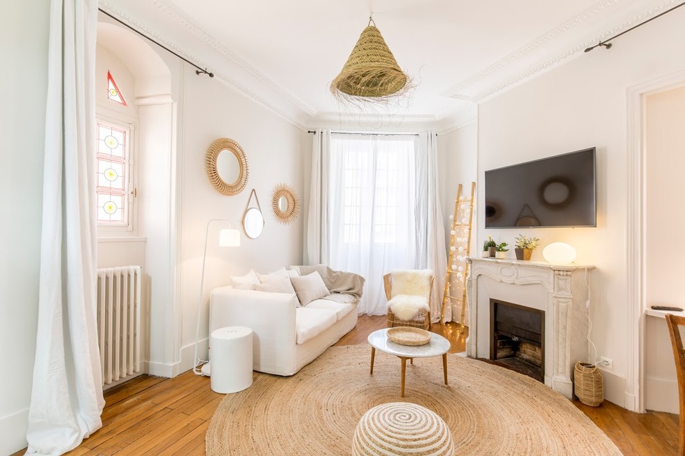 Esempio di un soggiorno stile marinaro con pareti bianche, pavimento in legno massello medio, camino classico, TV a parete e pavimento marrone