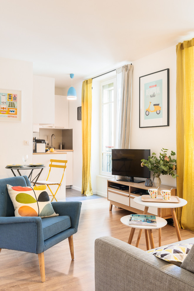Пример оригинального дизайна: маленькая открытая гостиная комната в скандинавском стиле с белыми стенами, светлым паркетным полом и отдельно стоящим телевизором для на участке и в саду