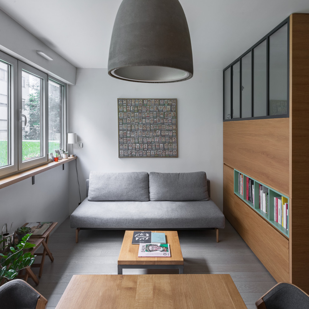 Kleines, Fernseherloses Nordisches Wohnzimmer ohne Kamin mit weißer Wandfarbe, gebeiztem Holzboden und grauem Boden in Paris
