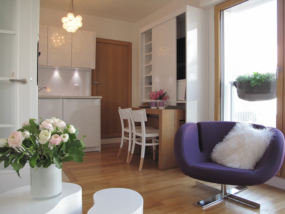 Modelo de sala de estar abierta actual pequeña sin chimenea y televisor con paredes blancas y suelo de madera en tonos medios