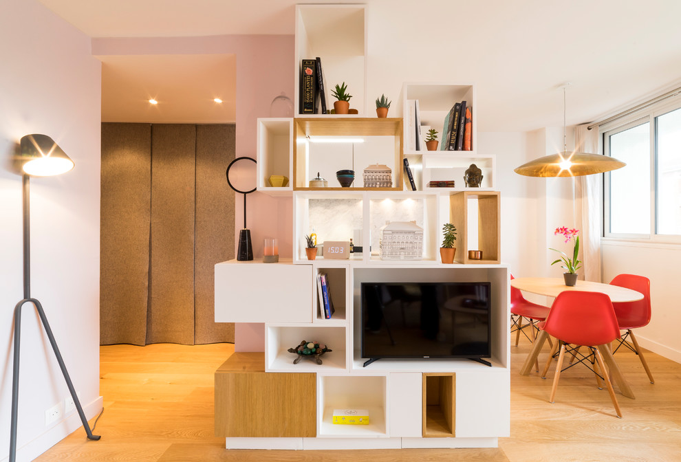 Immagine di un piccolo soggiorno minimal aperto con libreria, pareti rosa, parquet chiaro, nessun camino, parete attrezzata e pavimento marrone
