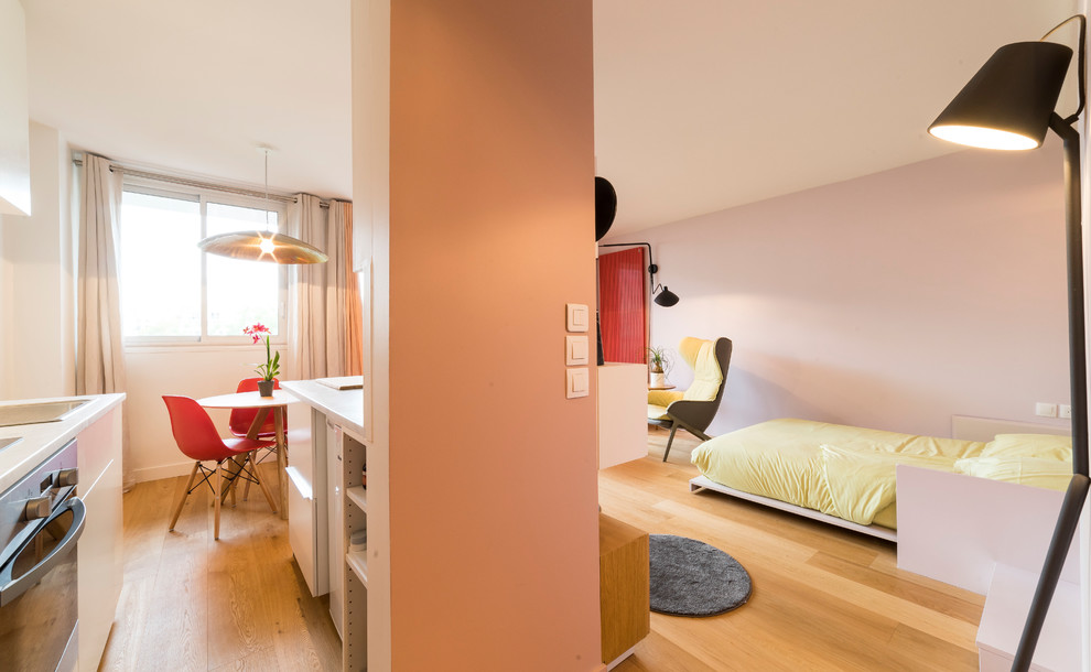 Ejemplo de sala de estar con biblioteca abierta contemporánea pequeña sin chimenea con paredes rosas, suelo de madera clara, pared multimedia y suelo marrón