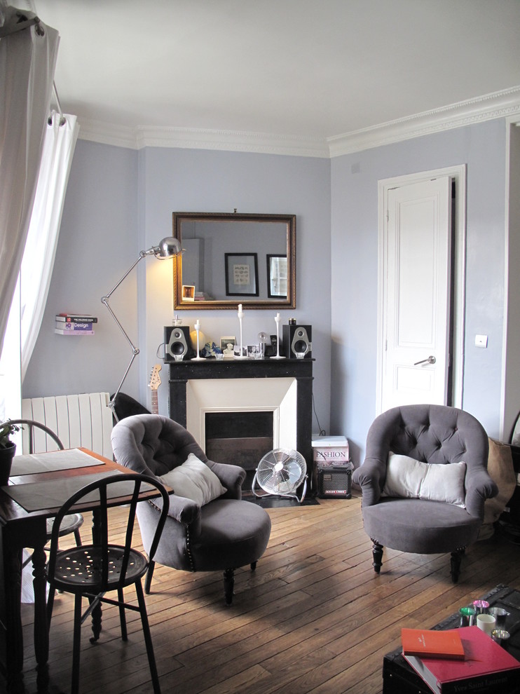 パリにあるお手頃価格の小さなトランジショナルスタイルのおしゃれな独立型ファミリールーム (無垢フローリング、標準型暖炉、石材の暖炉まわり、テレビなし、紫の壁) の写真