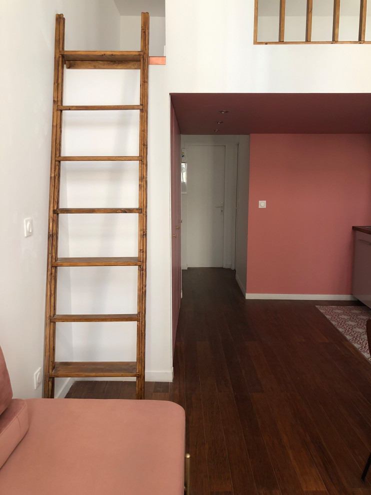 Пример оригинального дизайна: маленькая двухуровневая гостиная комната в современном стиле с розовыми стенами, полом из бамбука, стандартным камином, фасадом камина из штукатурки и коричневым полом для на участке и в саду