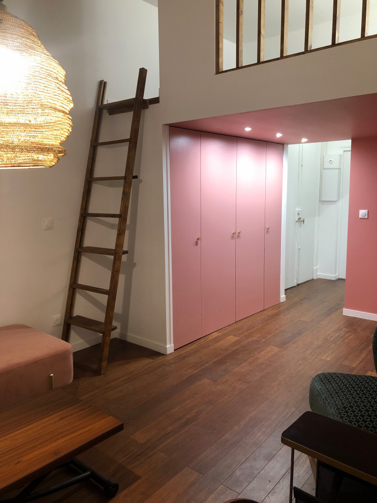 Ejemplo de sala de estar tipo loft contemporánea pequeña con paredes rosas, suelo de bambú, todas las chimeneas, marco de chimenea de yeso y suelo marrón