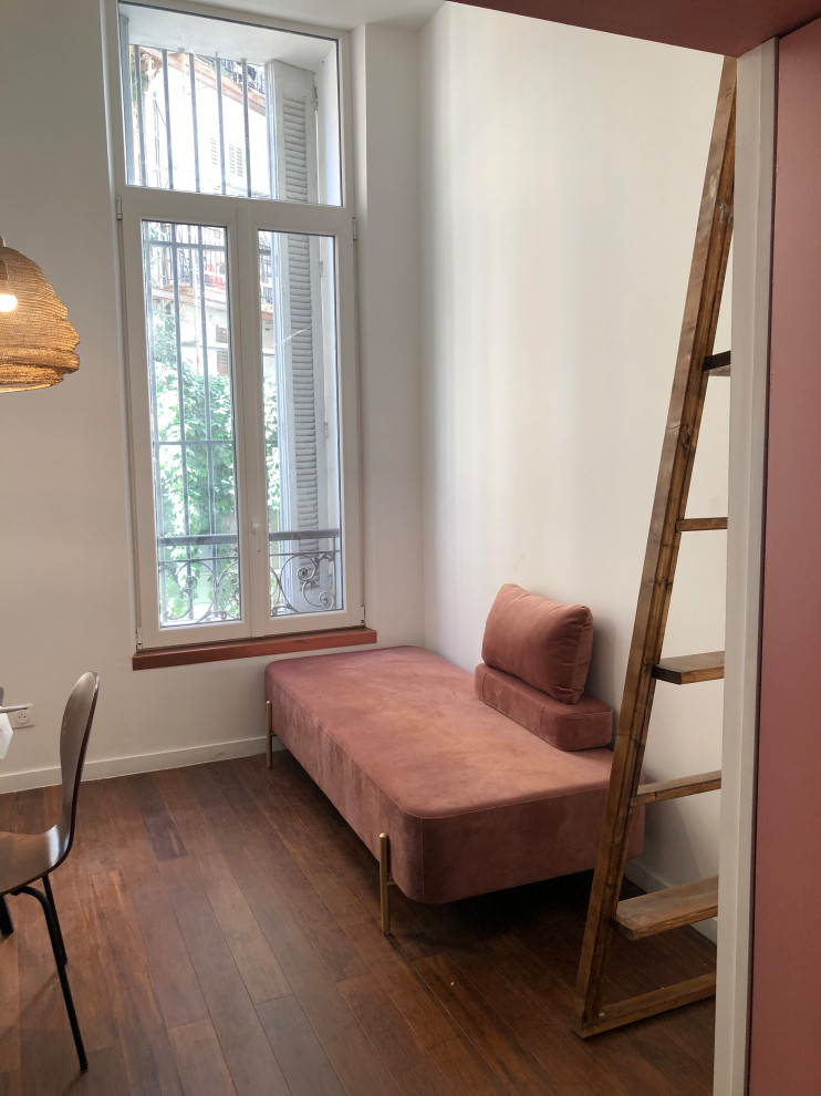 Foto de sala de estar tipo loft actual pequeña con paredes rosas, suelo de bambú, todas las chimeneas, marco de chimenea de yeso y suelo marrón