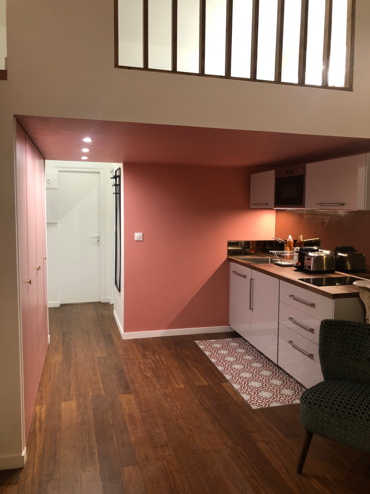 Aménagement d'une petite salle de séjour mansardée ou avec mezzanine contemporaine avec un mur rose, parquet en bambou, une cheminée standard, un manteau de cheminée en plâtre et un sol marron.