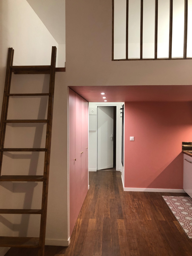 На фото: маленькая двухуровневая гостиная комната в современном стиле с розовыми стенами, полом из бамбука, стандартным камином, фасадом камина из штукатурки и коричневым полом для на участке и в саду