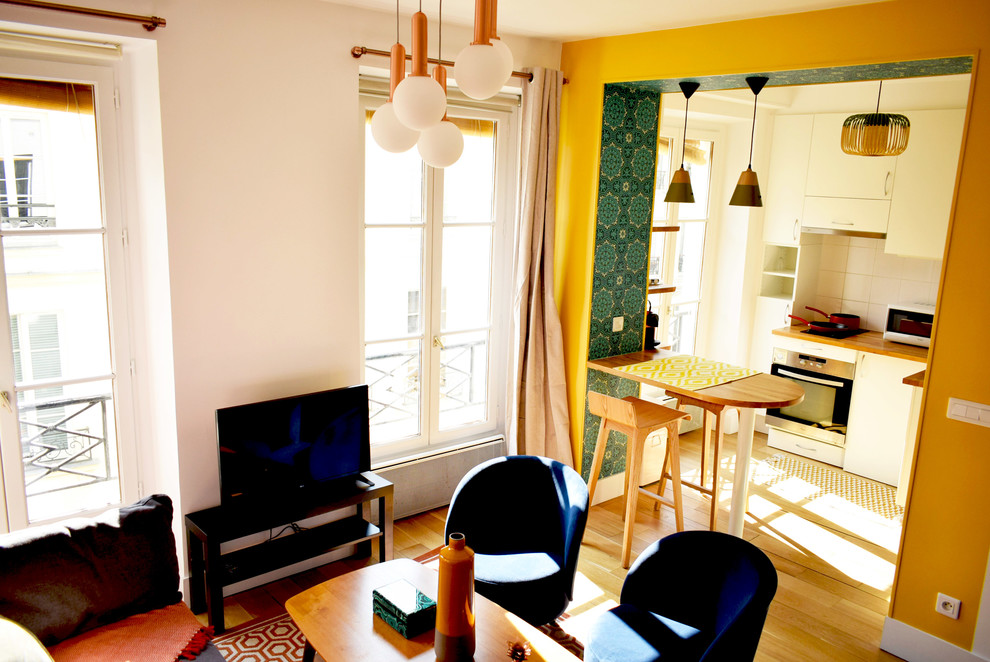 Cette photo montre une petite salle de séjour éclectique ouverte avec un mur jaune, un sol en bois brun et un téléviseur indépendant.