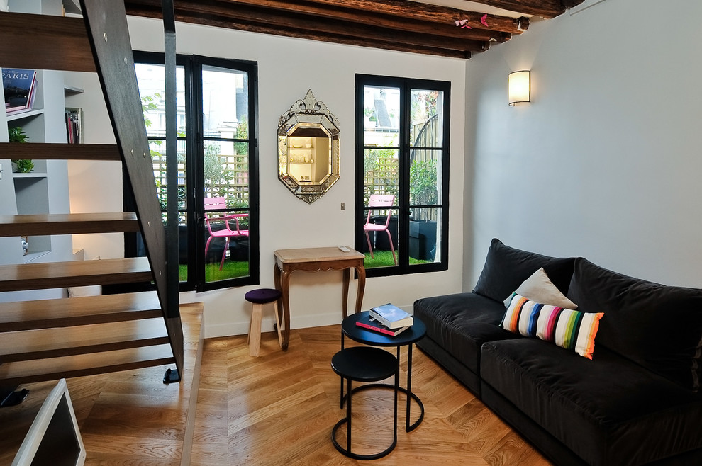 Exemple d'une salle de séjour tendance de taille moyenne et ouverte avec un mur blanc, un sol en bois brun, un téléviseur indépendant et un sol marron.
