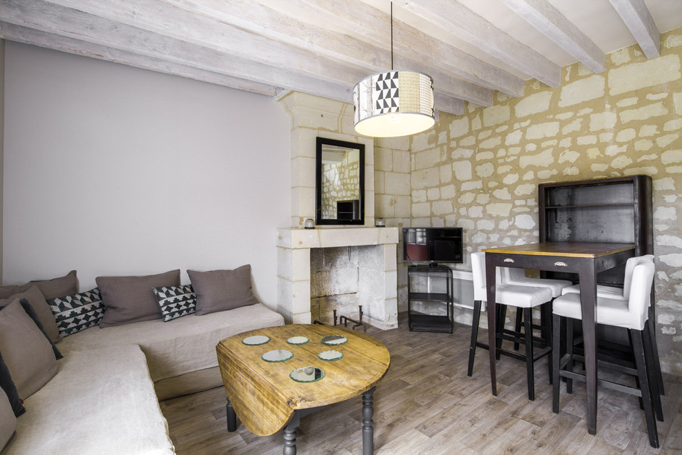 This is an example of a mediterranean games room in Angers with beige walls, medium hardwood flooring, a corner fireplace, a freestanding tv and brown floors.