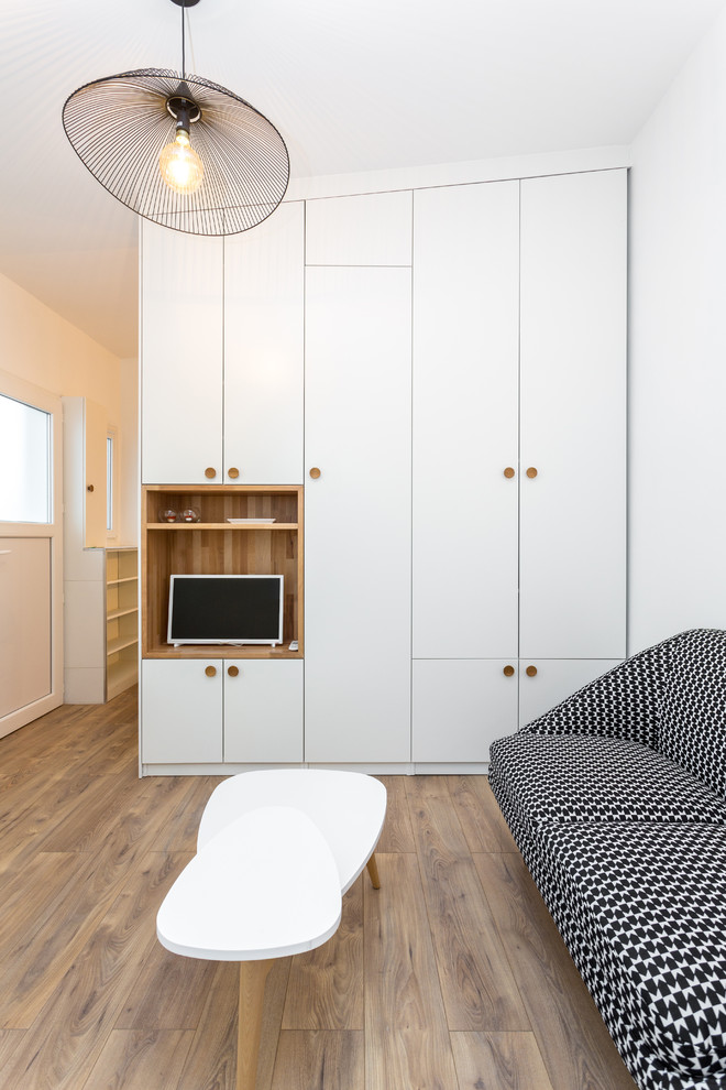 Idée de décoration pour une salle de séjour design de taille moyenne et ouverte avec parquet clair, un mur blanc, aucune cheminée, un téléviseur indépendant et un sol beige.