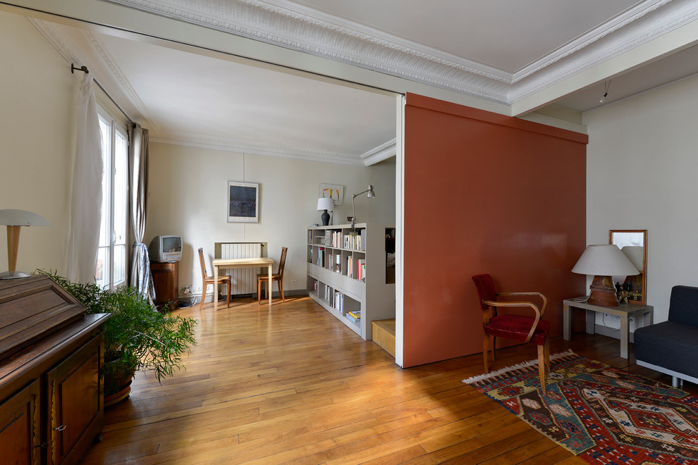 Modelo de sala de estar con biblioteca abierta tradicional de tamaño medio con paredes blancas, suelo de madera clara, televisor en una esquina y suelo beige
