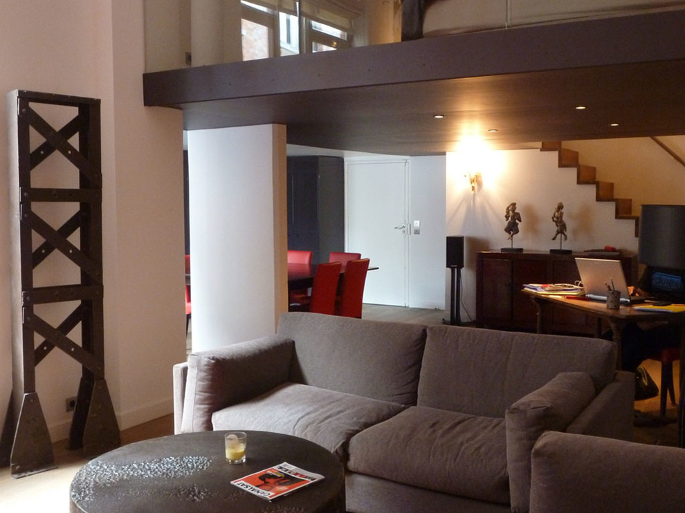 Cette image montre une grande salle de séjour design ouverte avec un mur blanc, parquet clair et un téléviseur fixé au mur.