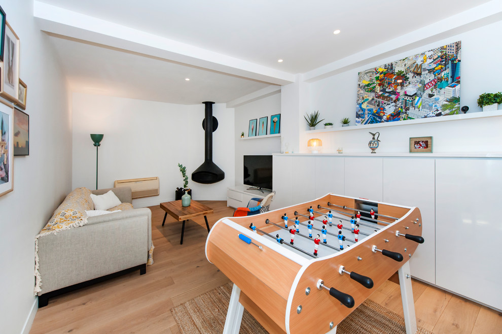 Aménagement d'une salle de séjour scandinave avec salle de jeu, un mur blanc, parquet clair, cheminée suspendue, un téléviseur indépendant et un sol beige.