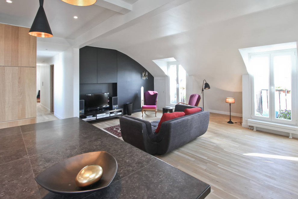 Стильный дизайн: большая двухуровневая гостиная комната в современном стиле с домашним баром, черными стенами, светлым паркетным полом и отдельно стоящим телевизором - последний тренд
