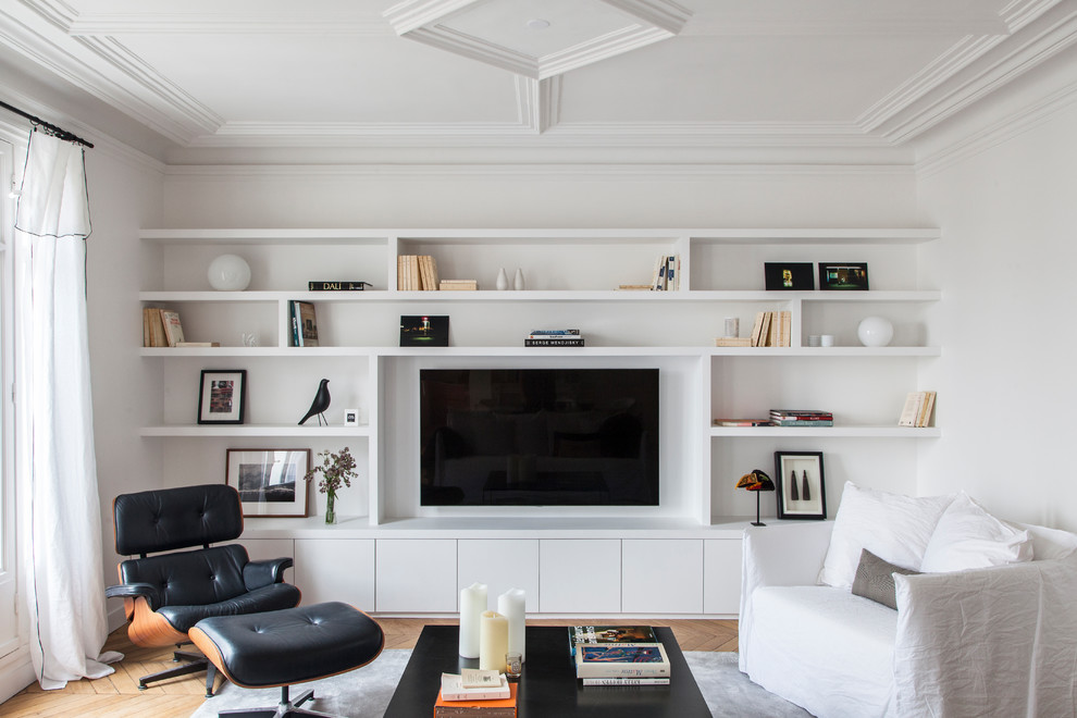 Modelo de sala de estar contemporánea sin chimenea con paredes blancas, pared multimedia y suelo de madera clara