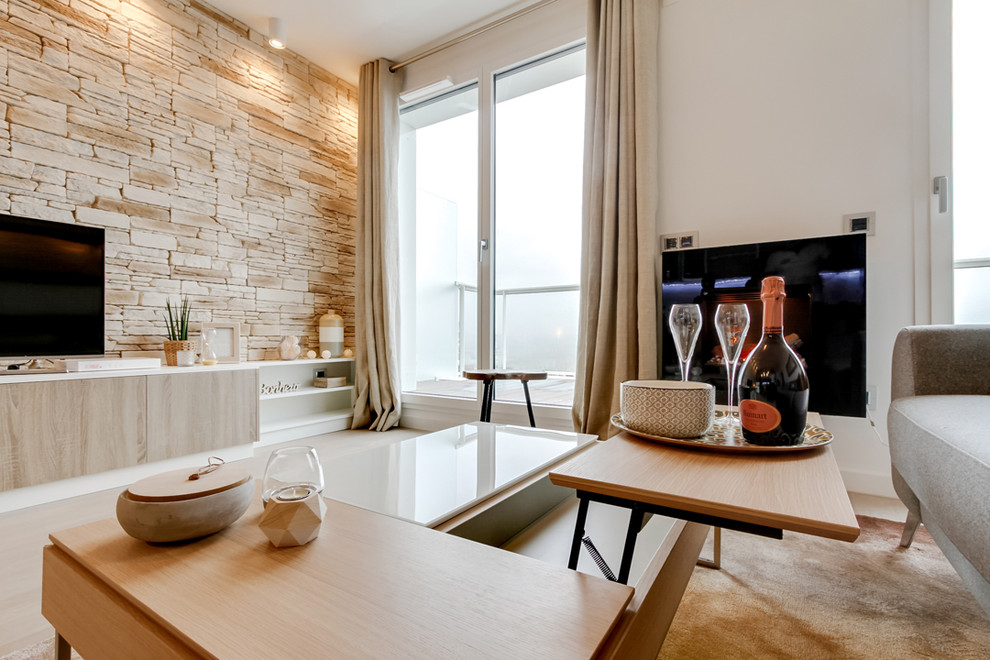 Mittelgroßes, Offenes Nordisches Wohnzimmer mit weißer Wandfarbe, hellem Holzboden, Hängekamin, Kaminumrandung aus Metall und freistehendem TV in Paris