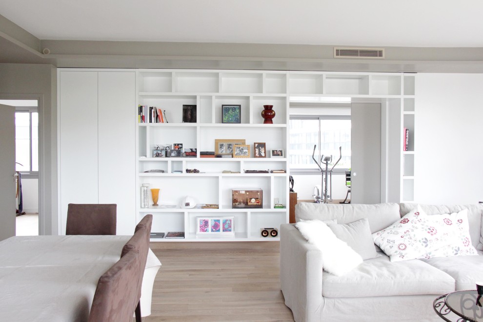 Esempio di un soggiorno minimal aperto e di medie dimensioni con pareti bianche, parquet chiaro e libreria