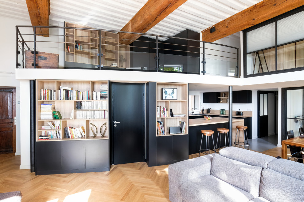 Design ideas for a large industrial open plan games room in Lyon with a reading nook, white walls, light hardwood flooring, no fireplace, no tv, brown floors and exposed beams.