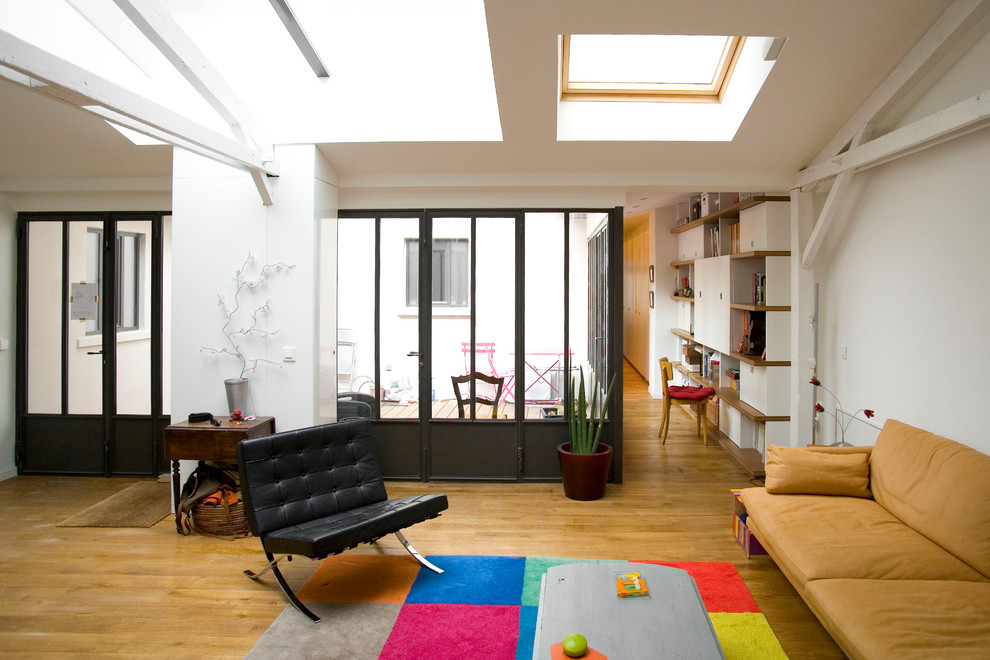 Imagen de sala de estar abierta industrial de tamaño medio sin televisor con paredes blancas y suelo de madera en tonos medios