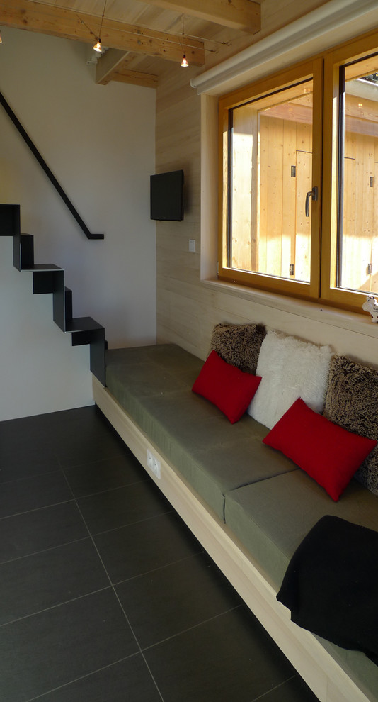 На фото: маленькая открытая гостиная комната в современном стиле с белыми стенами, полом из керамической плитки и телевизором на стене для на участке и в саду