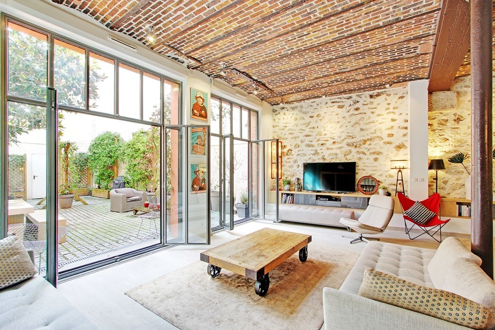 Großes, Offenes Mediterranes Wohnzimmer mit hellem Holzboden, beiger Wandfarbe, freistehendem TV und beigem Boden in Paris