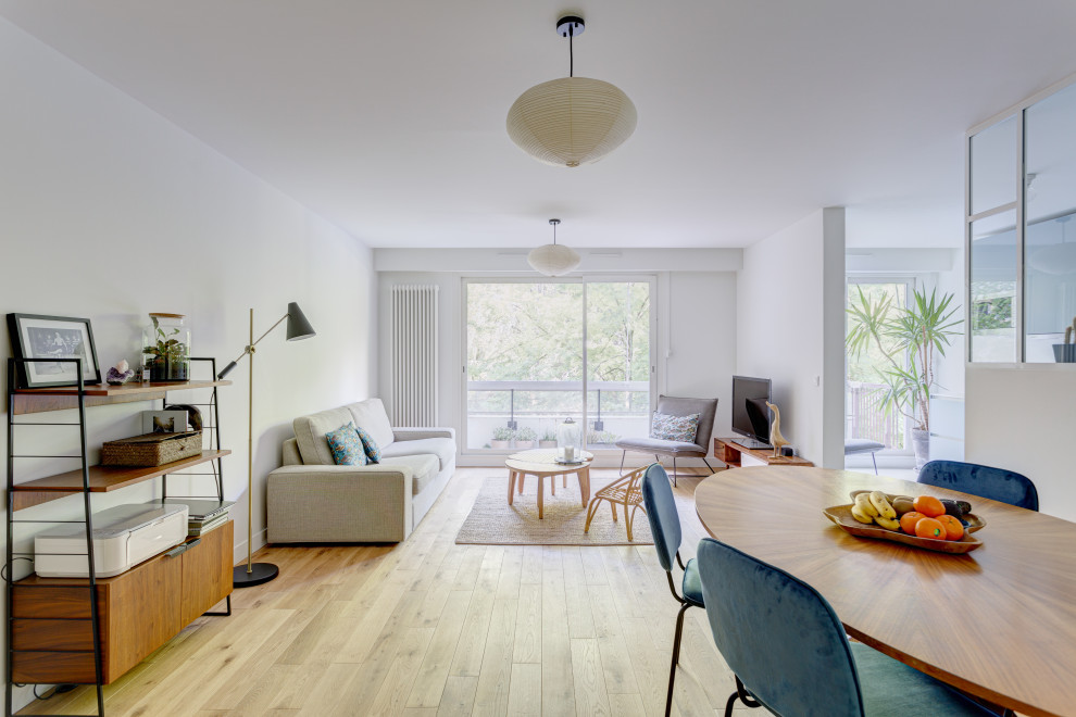 Großes, Offenes Skandinavisches Wohnzimmer mit weißer Wandfarbe, hellem Holzboden, freistehendem TV und beigem Boden in Paris