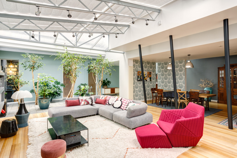Exemple d'une grande salle de séjour éclectique ouverte avec un mur multicolore, parquet clair, aucune cheminée, un téléviseur encastré et un sol beige.