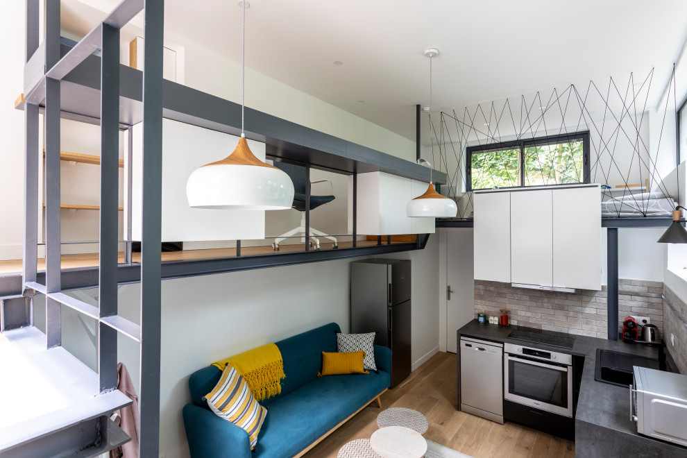 Diseño de sala de estar abierta contemporánea pequeña sin chimenea con paredes blancas, suelo de madera clara, televisor colgado en la pared y suelo marrón