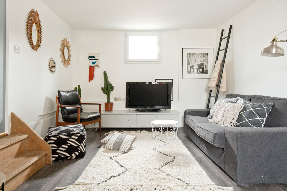 Abgetrenntes Skandinavisches Wohnzimmer ohne Kamin mit weißer Wandfarbe, braunem Holzboden und freistehendem TV in Paris