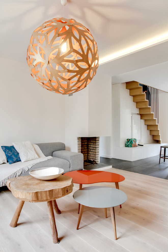 Foto de sala de estar abierta contemporánea de tamaño medio sin televisor con paredes blancas, suelo de madera clara y chimenea de esquina