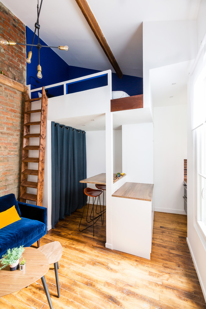 На фото: маленькая двухуровневая гостиная комната в стиле лофт с домашним баром, синими стенами, паркетным полом среднего тона, телевизором на стене и коричневым полом без камина для на участке и в саду с