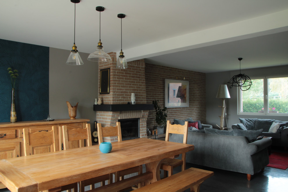 リールにある中くらいなコンテンポラリースタイルのおしゃれなオープンリビング (グレーの壁、コンクリートの床、薪ストーブ、レンガの暖炉まわり、グレーの床) の写真