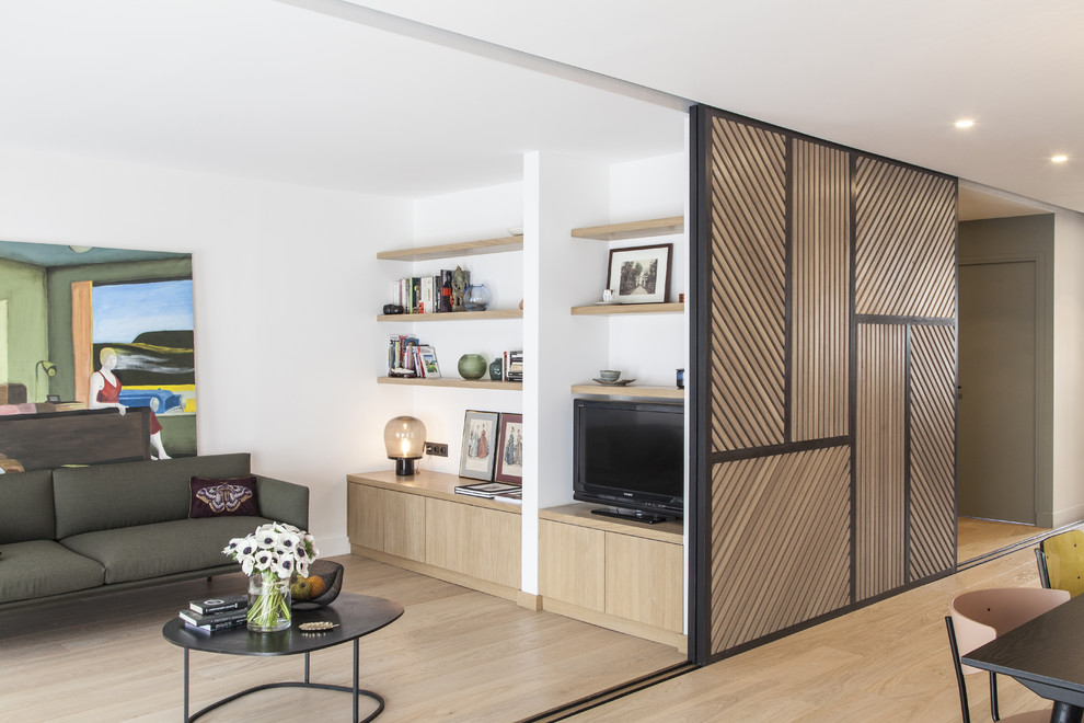Modelo de sala de estar con biblioteca abierta contemporánea de tamaño medio sin chimenea con paredes blancas, suelo de madera en tonos medios, televisor independiente y suelo marrón