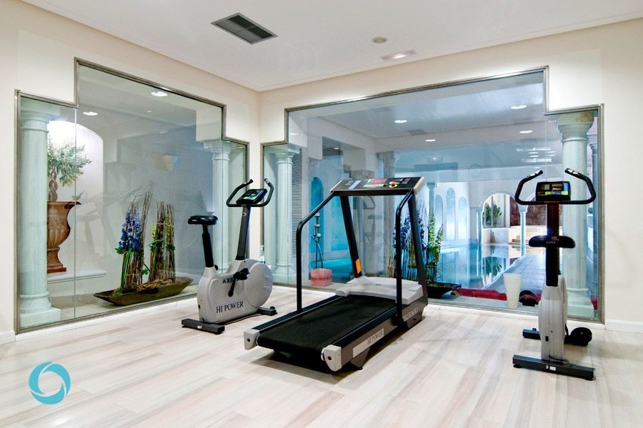 This is an example of a medium sized contemporary home weight room in Lyon with beige walls and light hardwood flooring.
