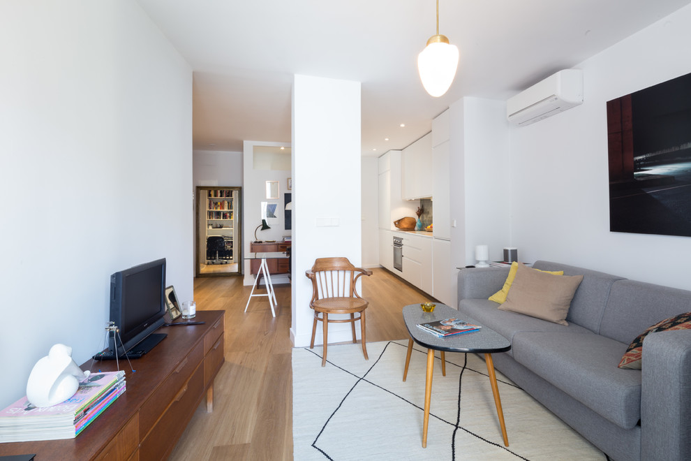 Foto de salón para visitas abierto minimalista de tamaño medio sin chimenea con paredes blancas, suelo de madera en tonos medios y televisor independiente