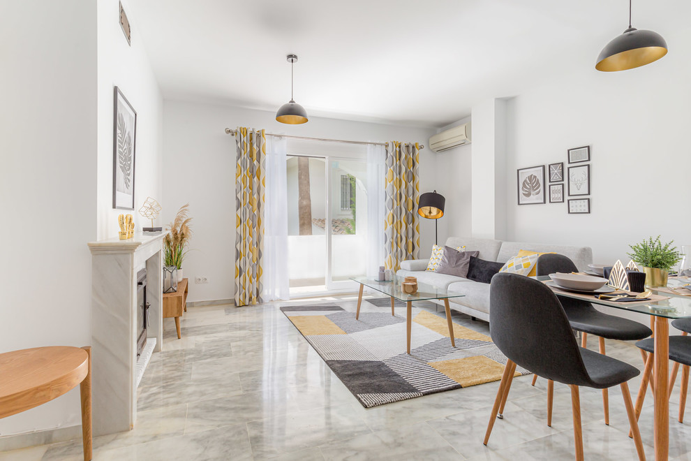 Kleines, Offenes Skandinavisches Wohnzimmer mit weißer Wandfarbe, Marmorboden, Kamin, Kaminumrandung aus Stein und grauem Boden in Malaga