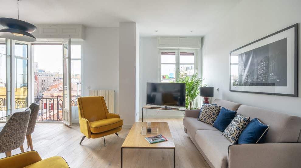 Imagen de salón abierto contemporáneo pequeño con paredes blancas, suelo de madera clara, suelo beige y televisor en una esquina