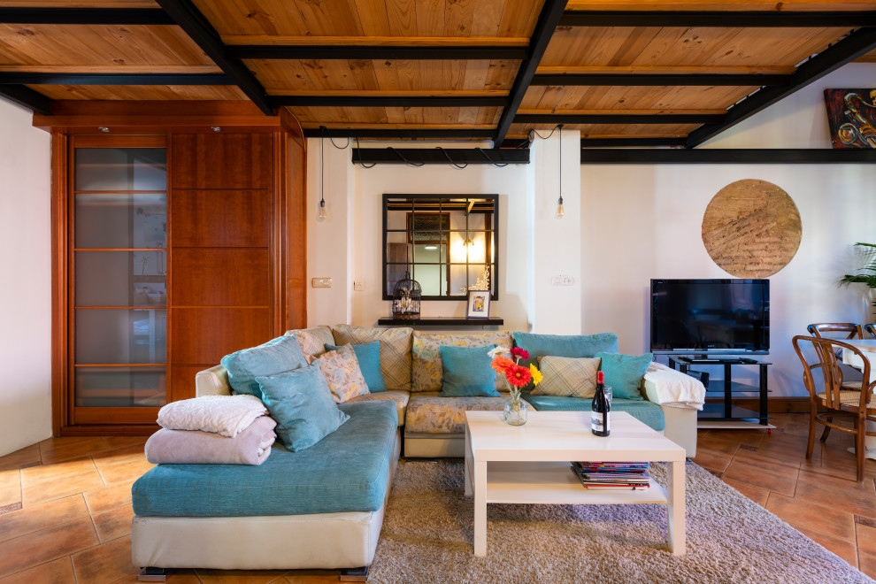 This is an example of a bohemian open plan living room in Valencia with white walls, brown floors and a wood ceiling.
