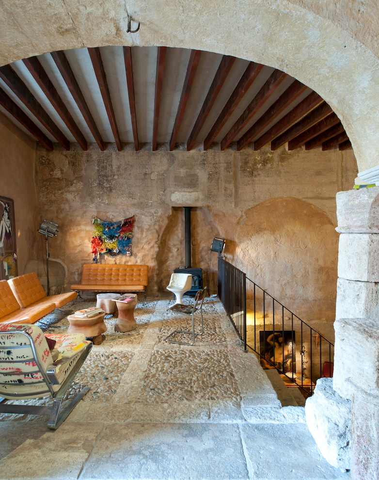 Ejemplo de salón tipo loft mediterráneo de tamaño medio sin televisor con suelo beige, paredes beige, estufa de leña, marco de chimenea de metal y piedra