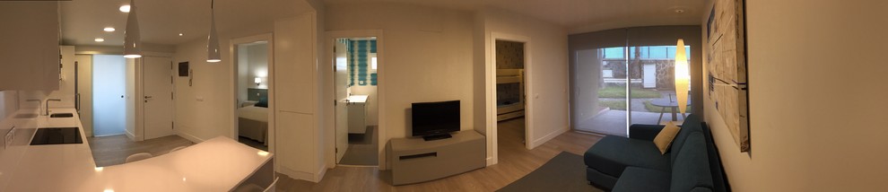 Imagen de salón abierto moderno pequeño con paredes blancas, suelo laminado y suelo beige
