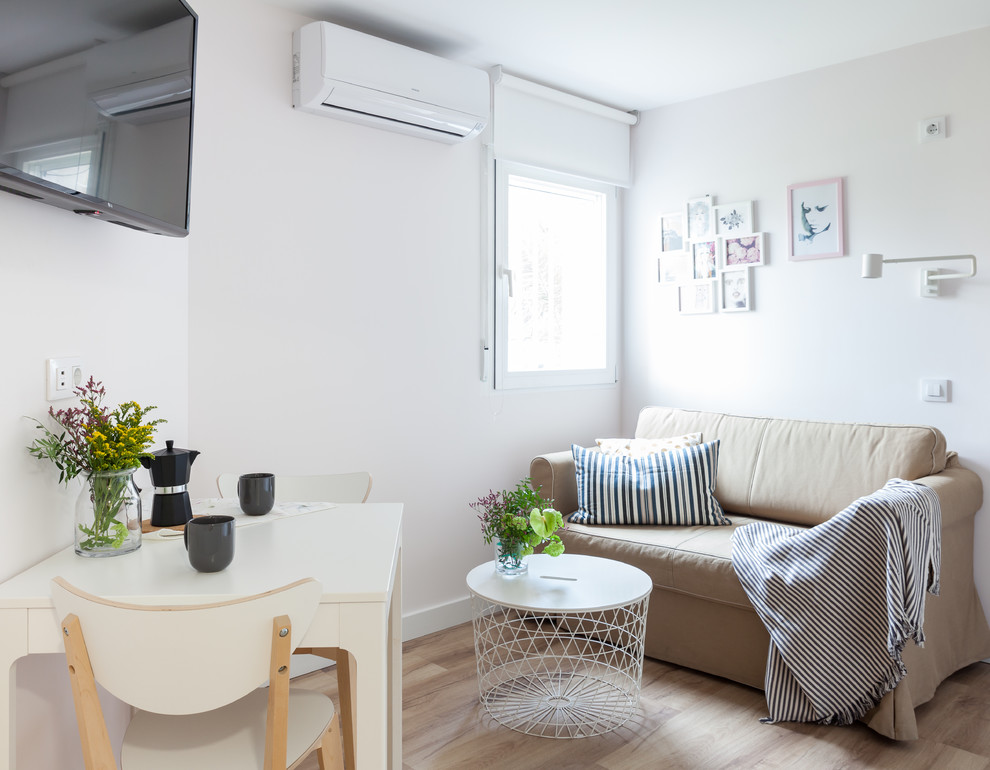 Kleines, Offenes Skandinavisches Wohnzimmer mit weißer Wandfarbe, Laminat, TV-Wand und braunem Boden in Madrid