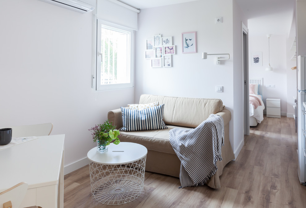 Идея дизайна: маленькая открытая гостиная комната в скандинавском стиле с белыми стенами, полом из ламината, телевизором на стене и коричневым полом для на участке и в саду