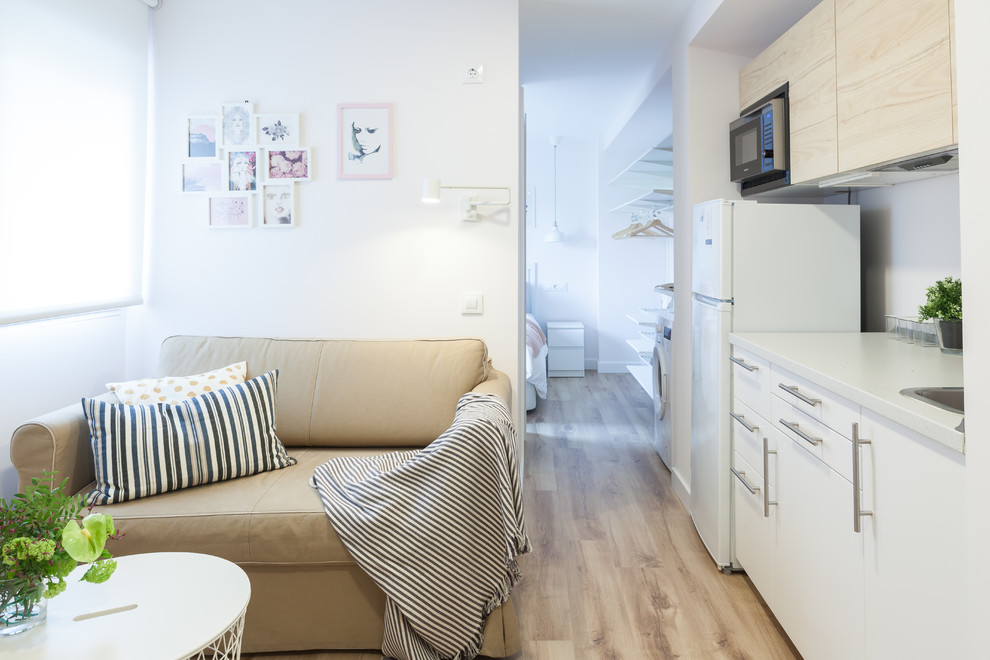 Aménagement d'un petit salon scandinave ouvert avec un mur blanc, sol en stratifié, un téléviseur fixé au mur et un sol marron.