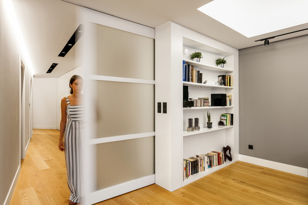 Imagen de salón abierto actual con paredes grises y suelo de madera en tonos medios